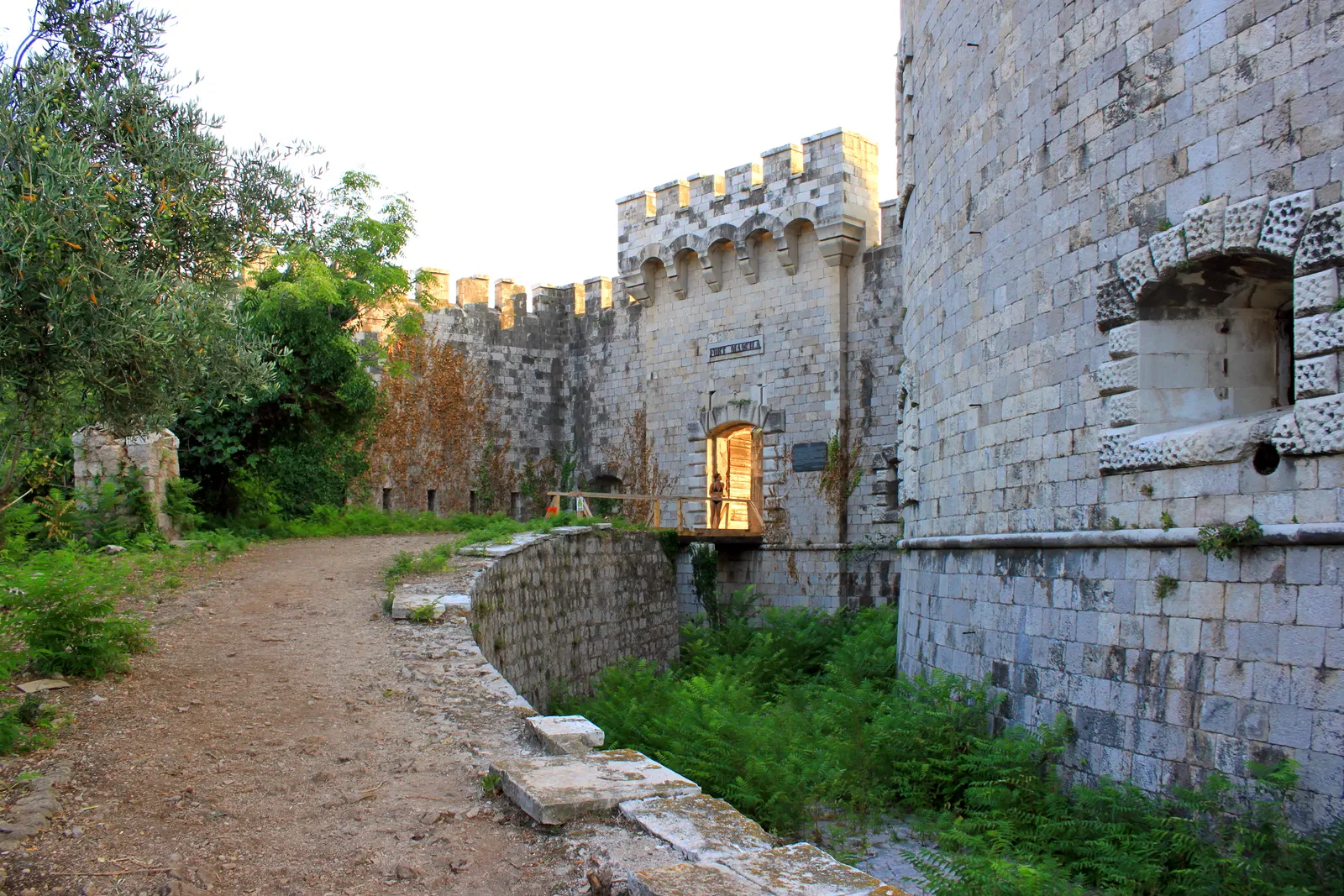 The thick stone ramparts and gate of Fort Mamula, the round Austro-Hungarian island fortress at the mouth of the Bay of Kotor