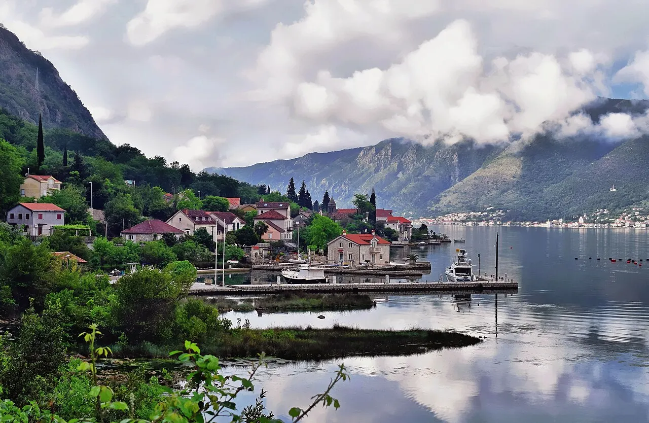 The calm Dobrota waterfront on the Bay of Kotor, a low level jetty and stone houses reflected in still water