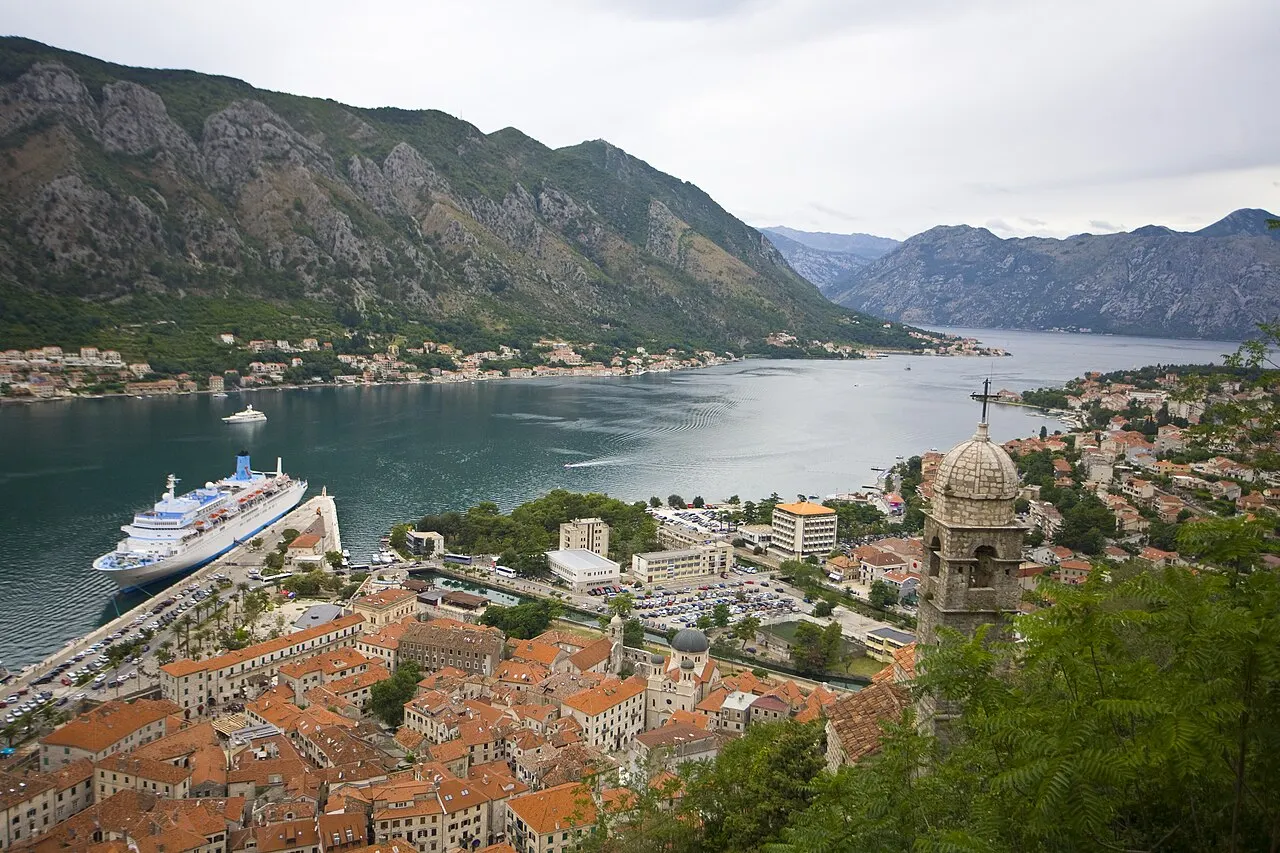 The Bay of Kotor panorama from an elevated viewpoint, the Old Town and a cruise ship below, the fjord between the mountains