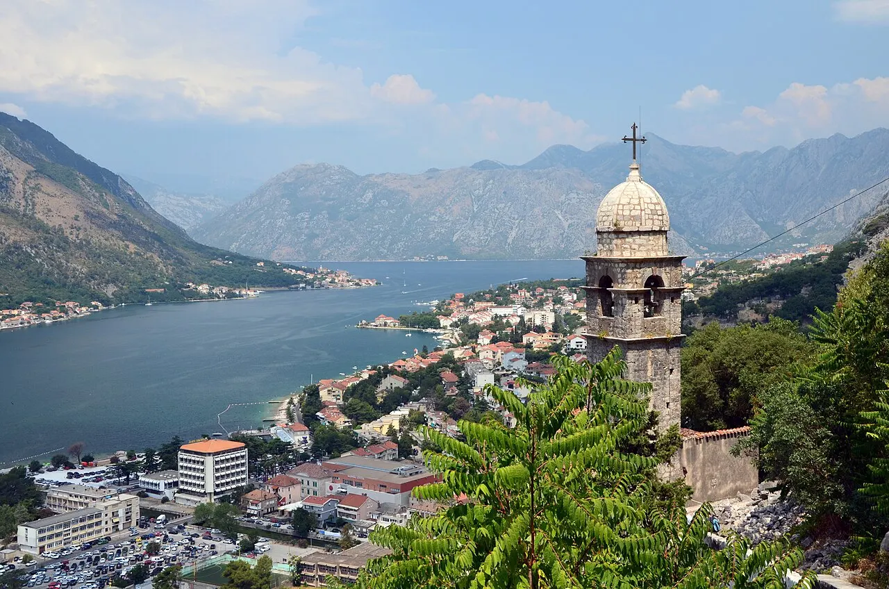 The Church of Our Lady of Remedy bell tower with Kotor's roofs and the bay below, seen from the halfway terrace