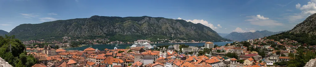 A bay-side view of Kotor with the town below its towering walls, the kind of village base near the old town