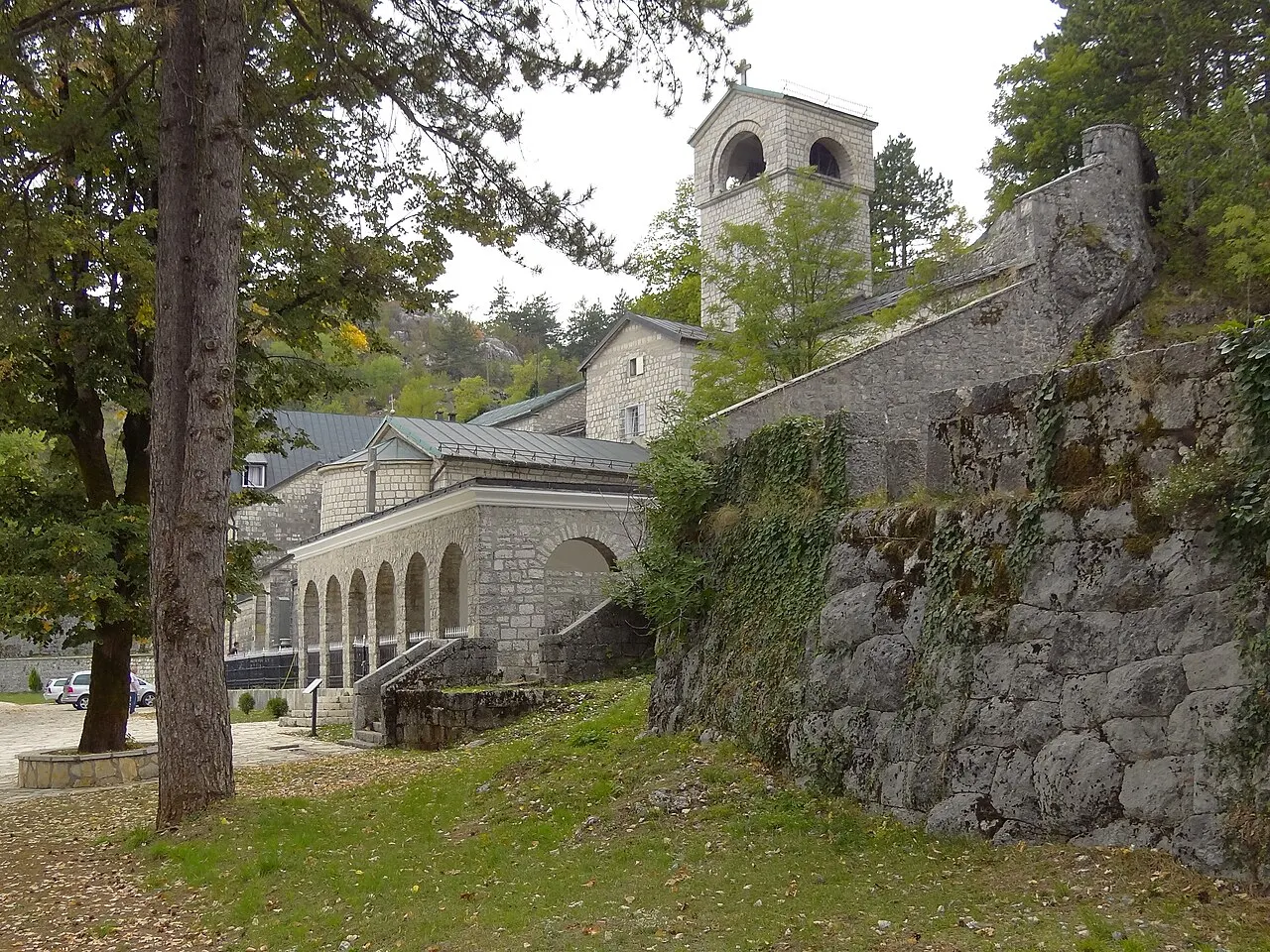 The Cetinje Monastery with its arcaded stone facade, bell tower and chapel set against the bare rocky Lovćen hillside