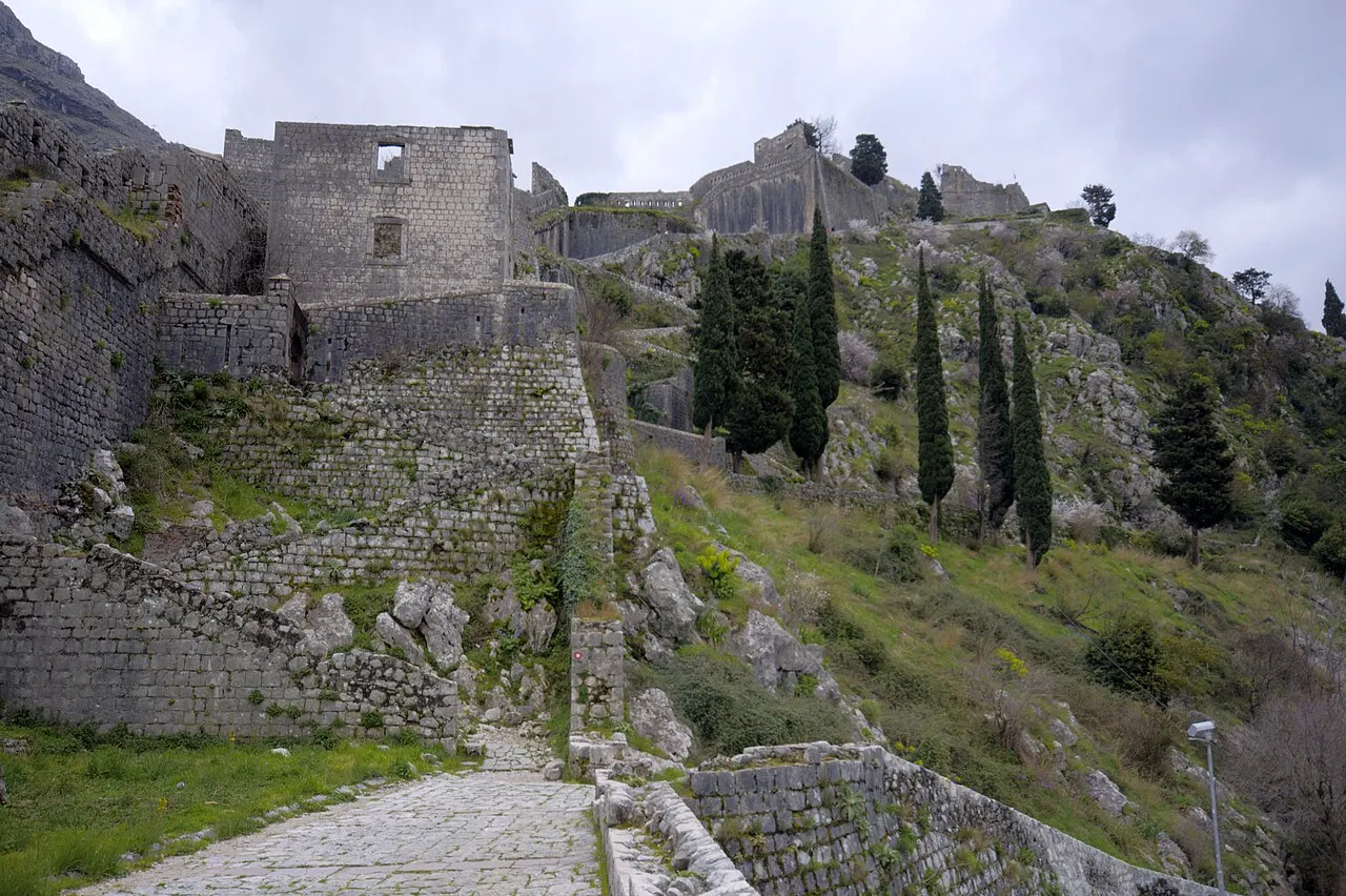 The cobbled lower path and stone steps at the start of the climb to St John's fortress, walls rising up the hillside