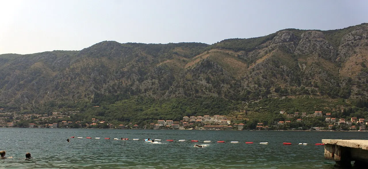 A concrete bathing platform off the Dobrota waterfront, swimmers in the clear deep bay water