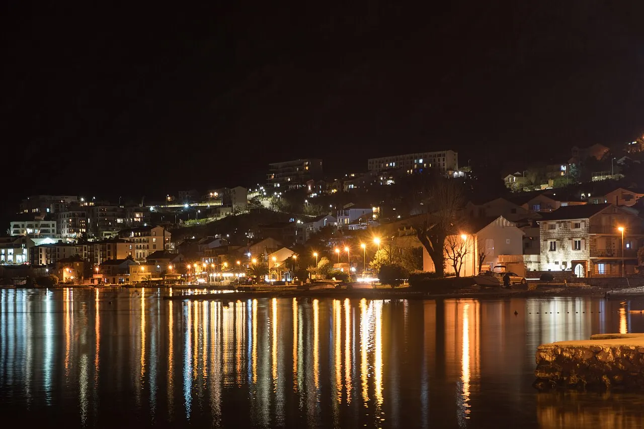 The Dobrota shore after dark, town lights reflected across the still waters of Kotor Bay