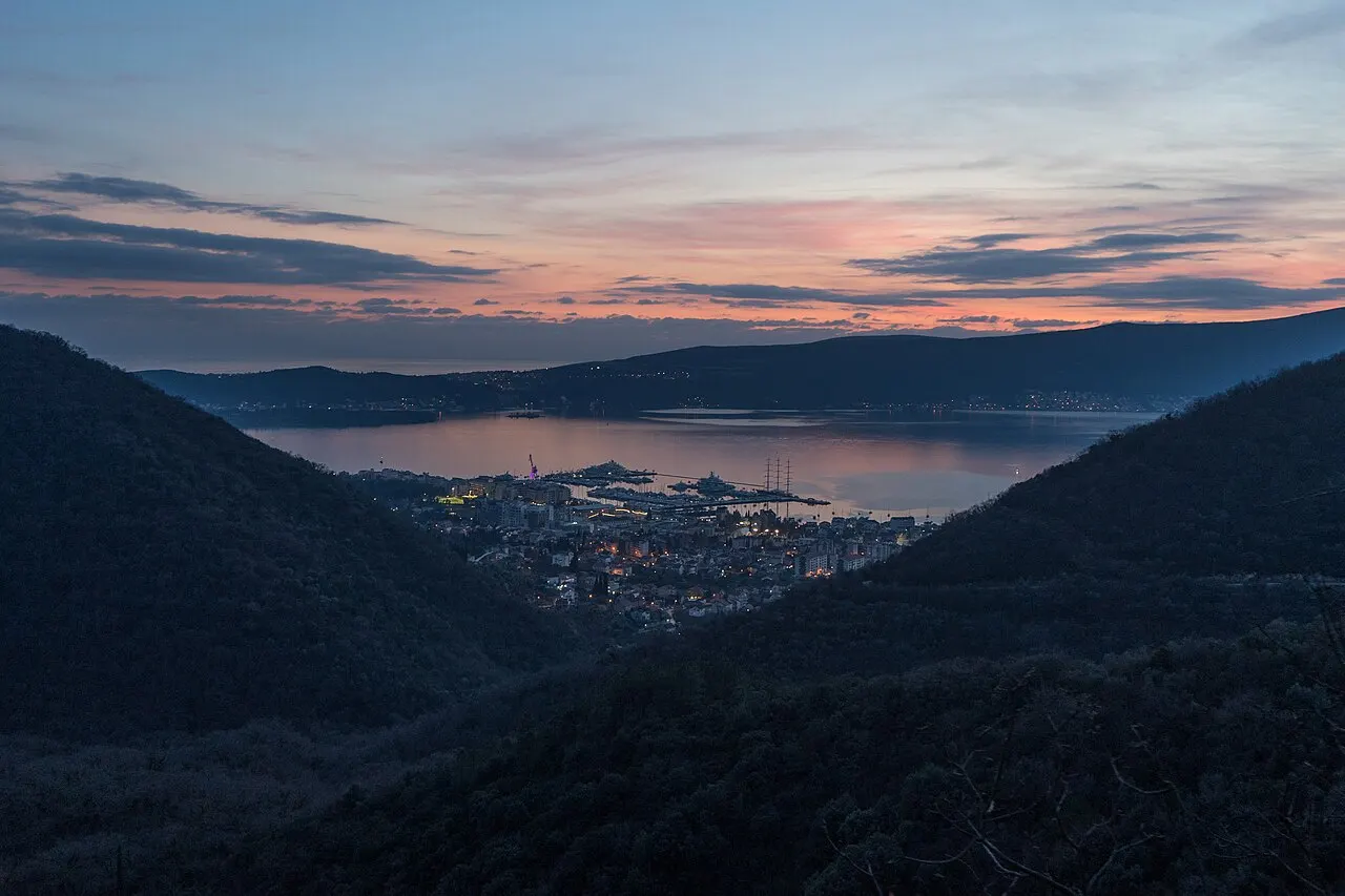 The Bay of Kotor glowing at sunset over still water beneath the mountains