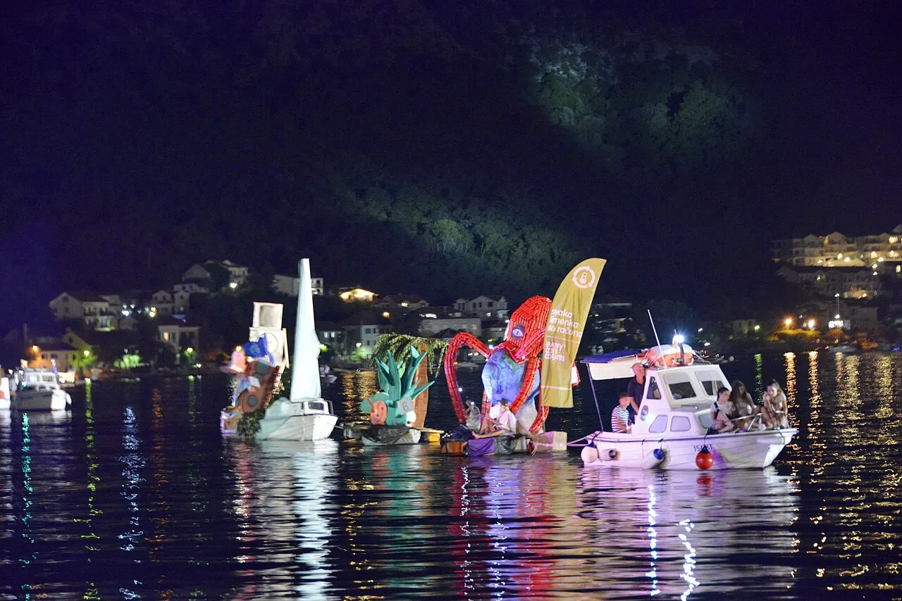 Illuminated and decorated boats parading on the bay during Boka Night in Kotor