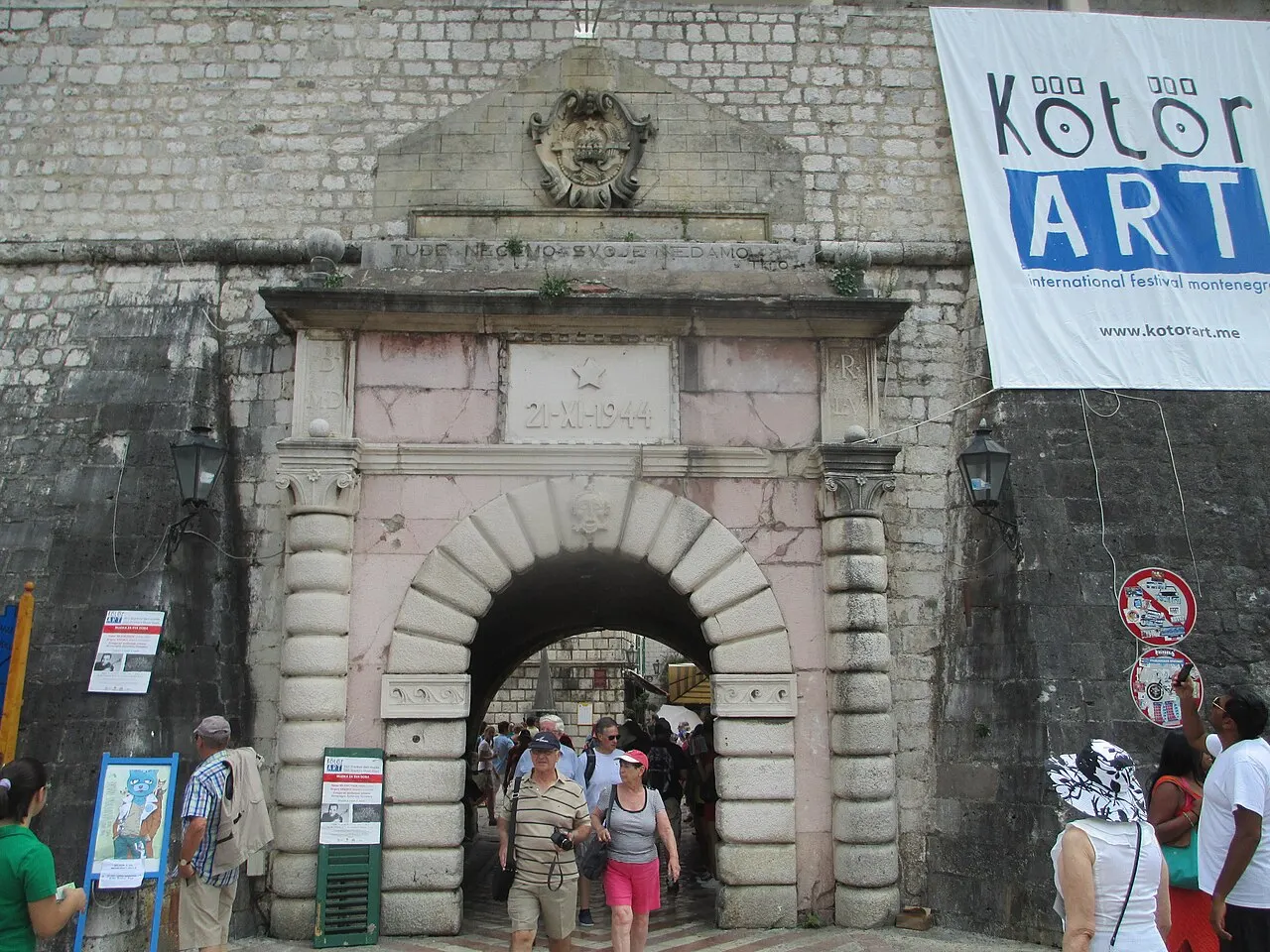 Visitors walking through the stone Sea Gate into Kotor Old Town