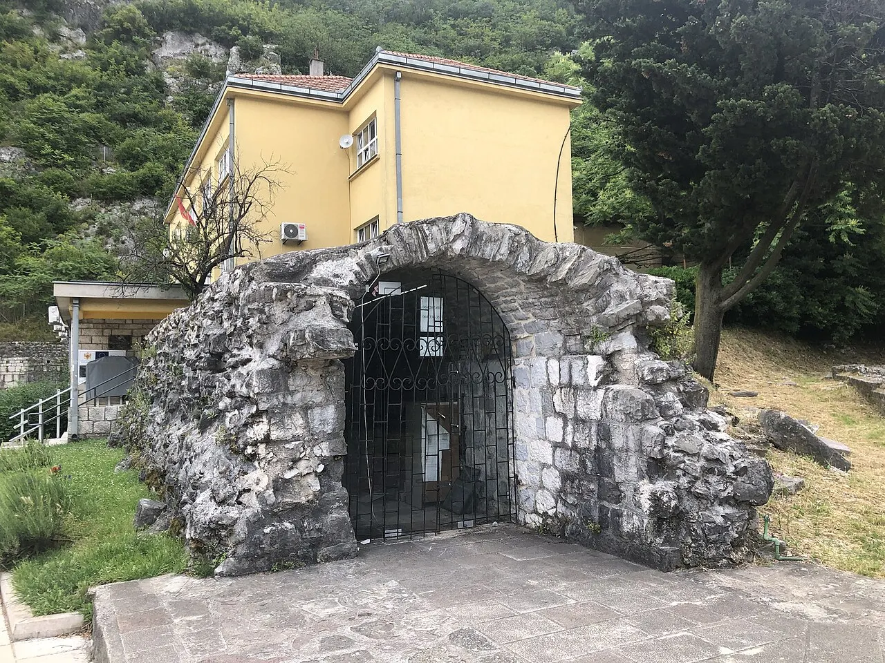 A small stone-walled, stone-paved courtyard with potted plants in Kotor Old Town