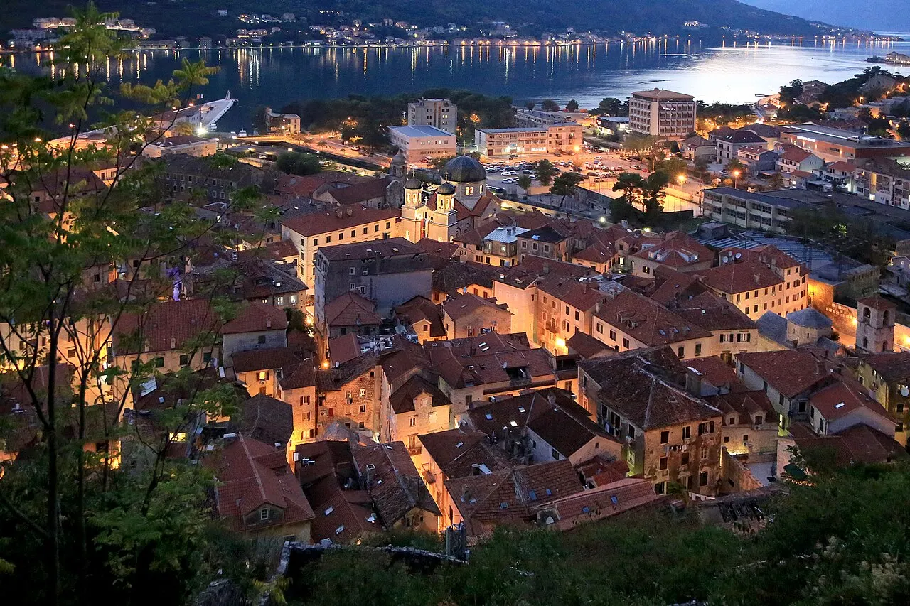Kotor's old town and bay at blue hour, the lamplit rooftops quiet beneath the dusk sky