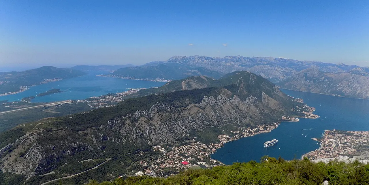 A cruise ship moored on the Bay of Kotor beside the Old Town, the mountains rising behind