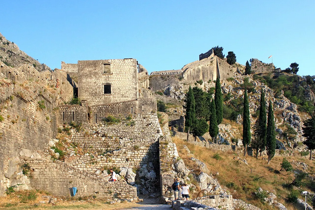 Sun-baked stone steps and fortress ruins on the shadeless climb above Kotor under a clear sky