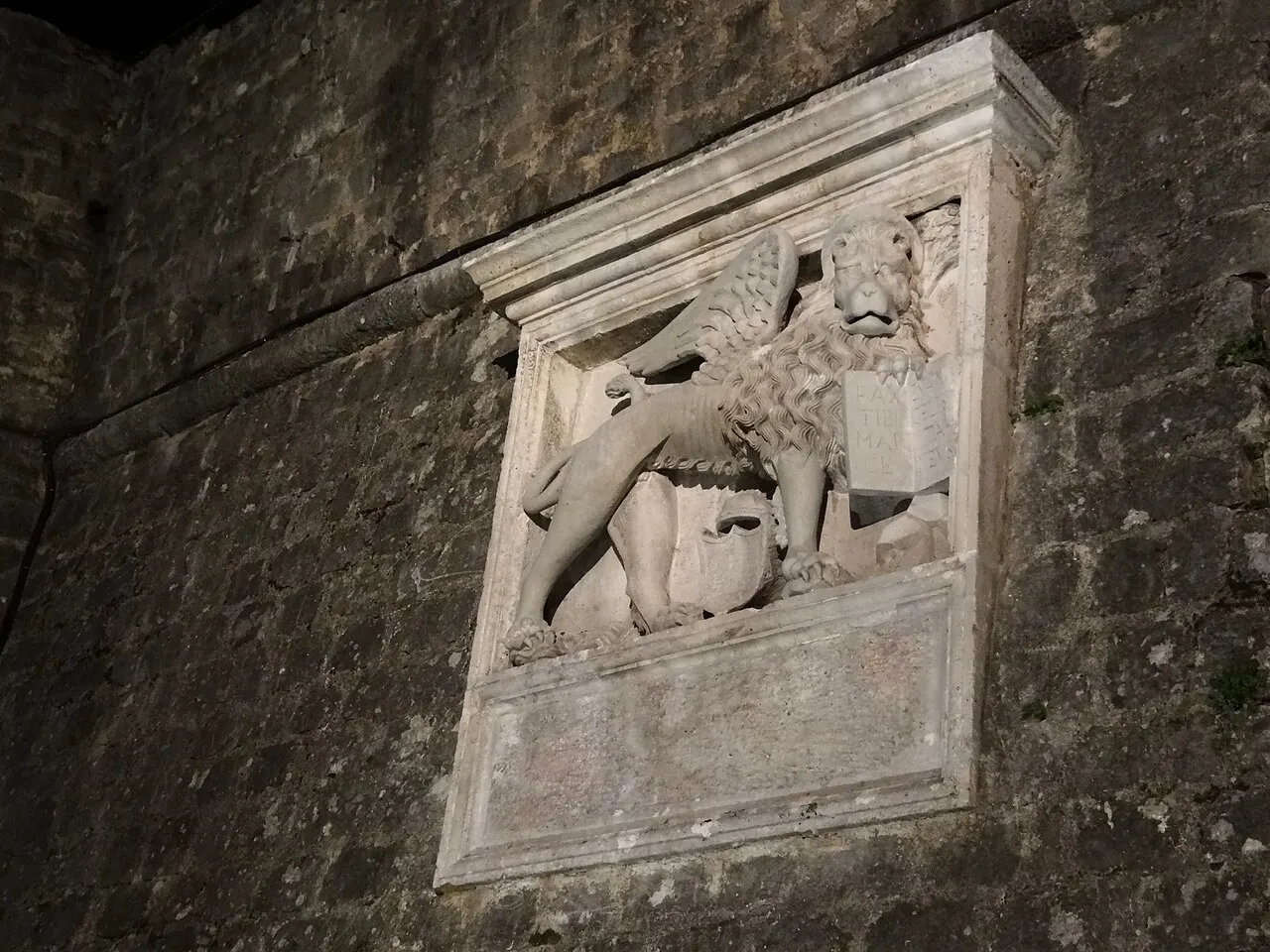 The floodlit Old Town walls of Kotor at night, the Venetian winged-lion relief picked out in light
