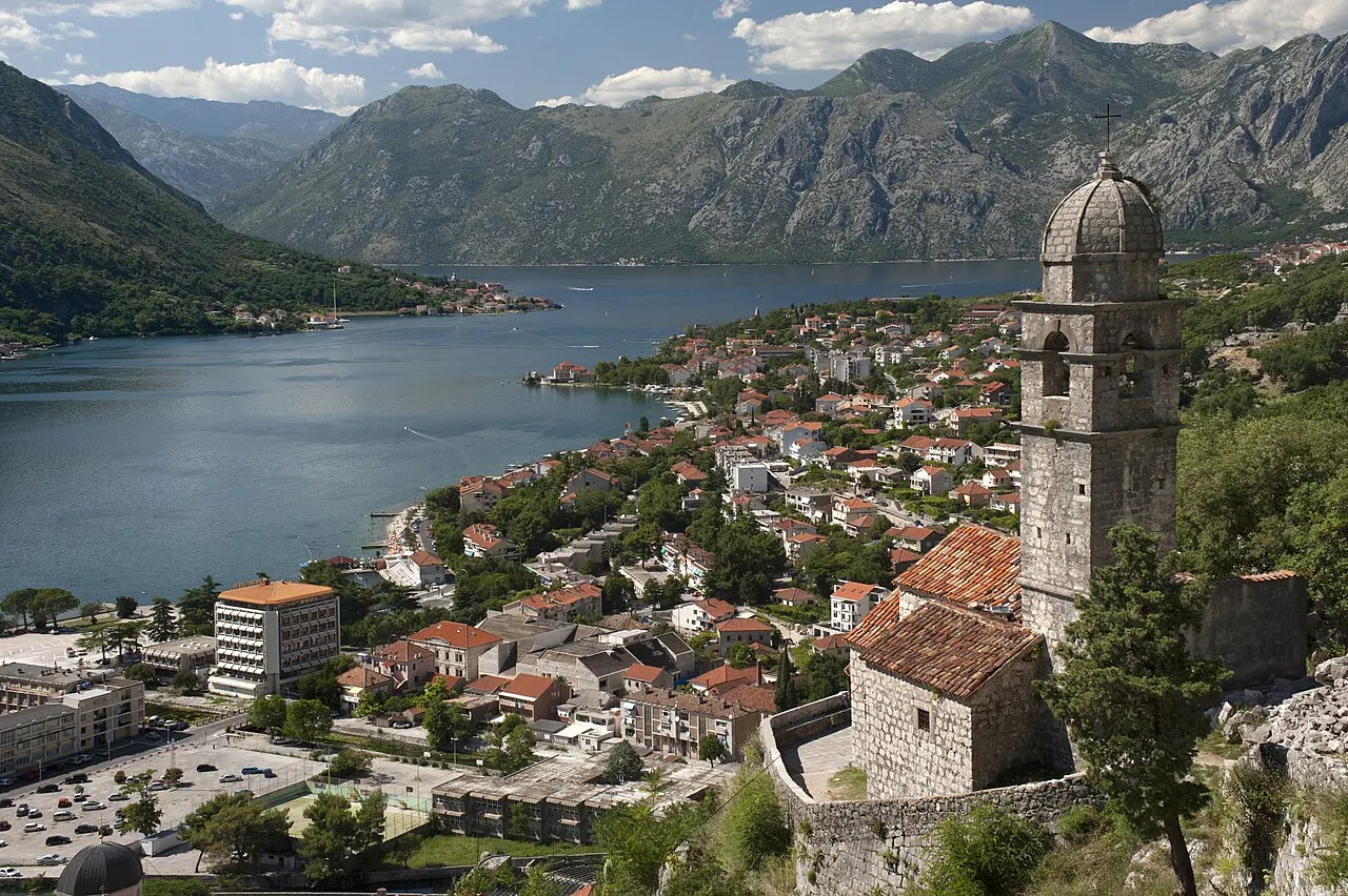 View past the Church of Our Lady of Remedy over Kotor's roofs and the bay toward the strait
