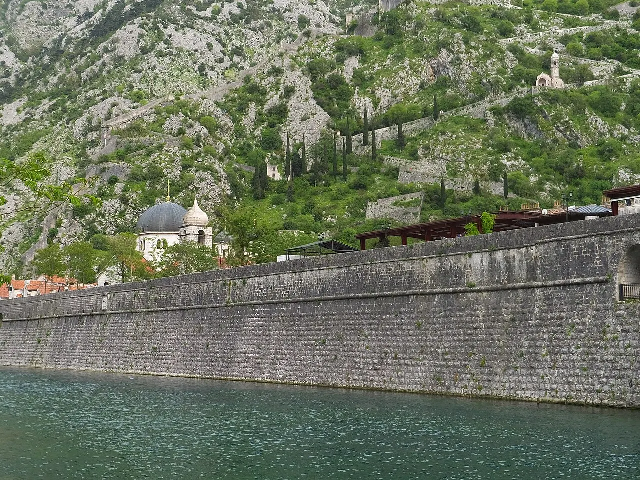 Kotor's city walls climbing the mountainside toward the white chapel of Our Lady of Remedy