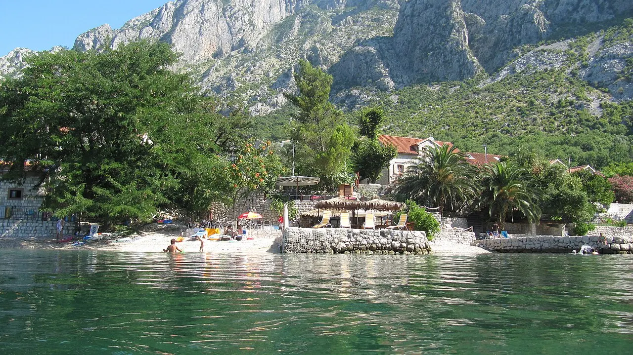 Clear green water off an Orahovac beach platform on the Bay of Kotor, steep mountains rising behind