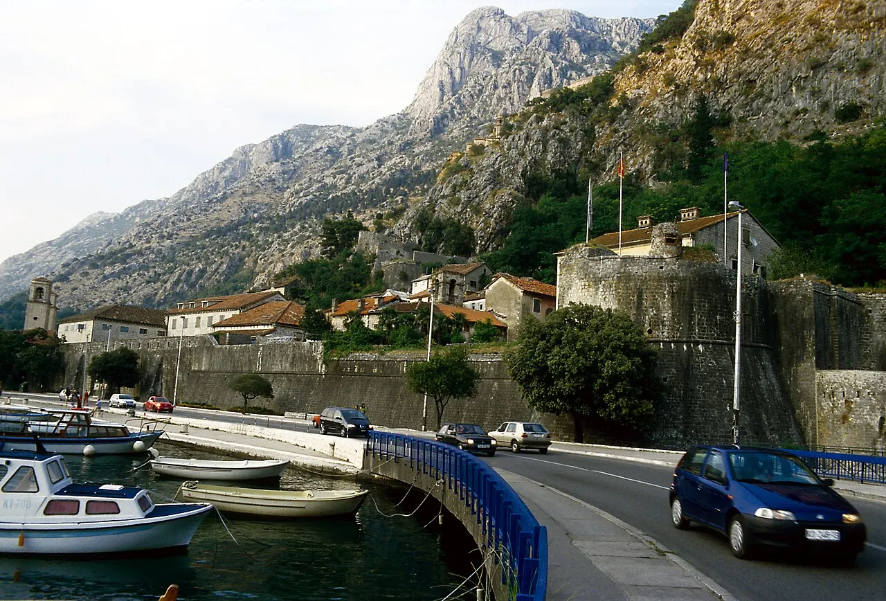 Cars on the main road and boats moored along the waterfront just outside Kotor's Old Town walls