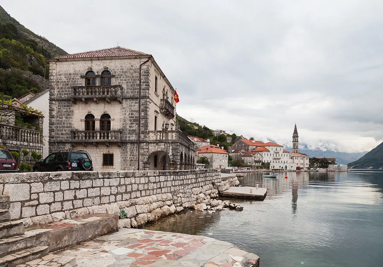 A baroque captains' palace and the tall stone bell tower of St Nicholas on the Perast waterfront