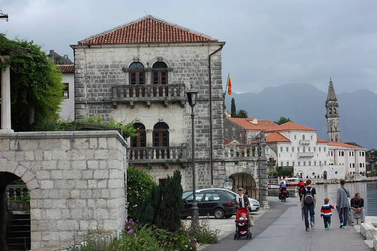 The Perast waterfront promenade past stone palaces toward the St Nicholas bell tower