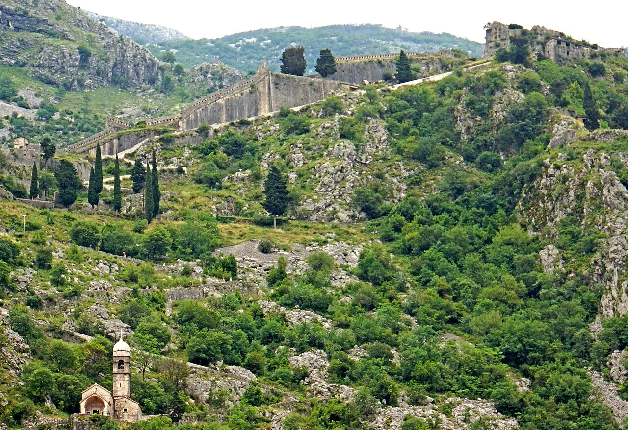 Kotor's medieval ramparts switchbacking up the cliff toward the fortress, the Church of Our Lady of Remedy below