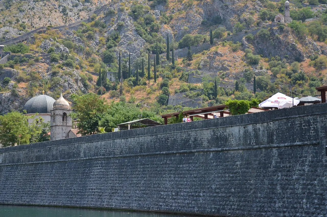 A quiet stretch of Kotor's city walls with the rooftops and bay below