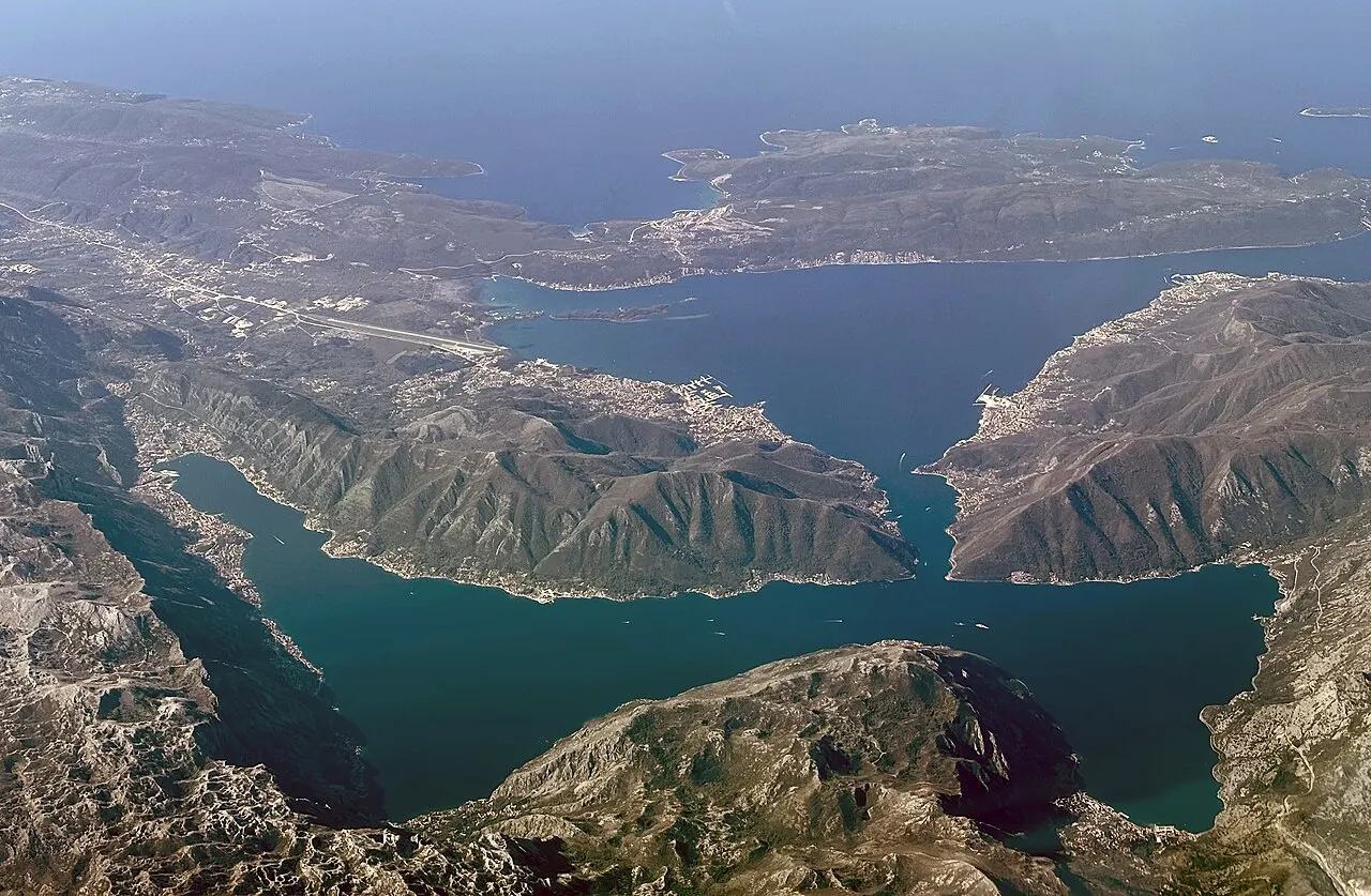 Aerial view down onto the whole glowing Bay of Kotor ringed by mountains