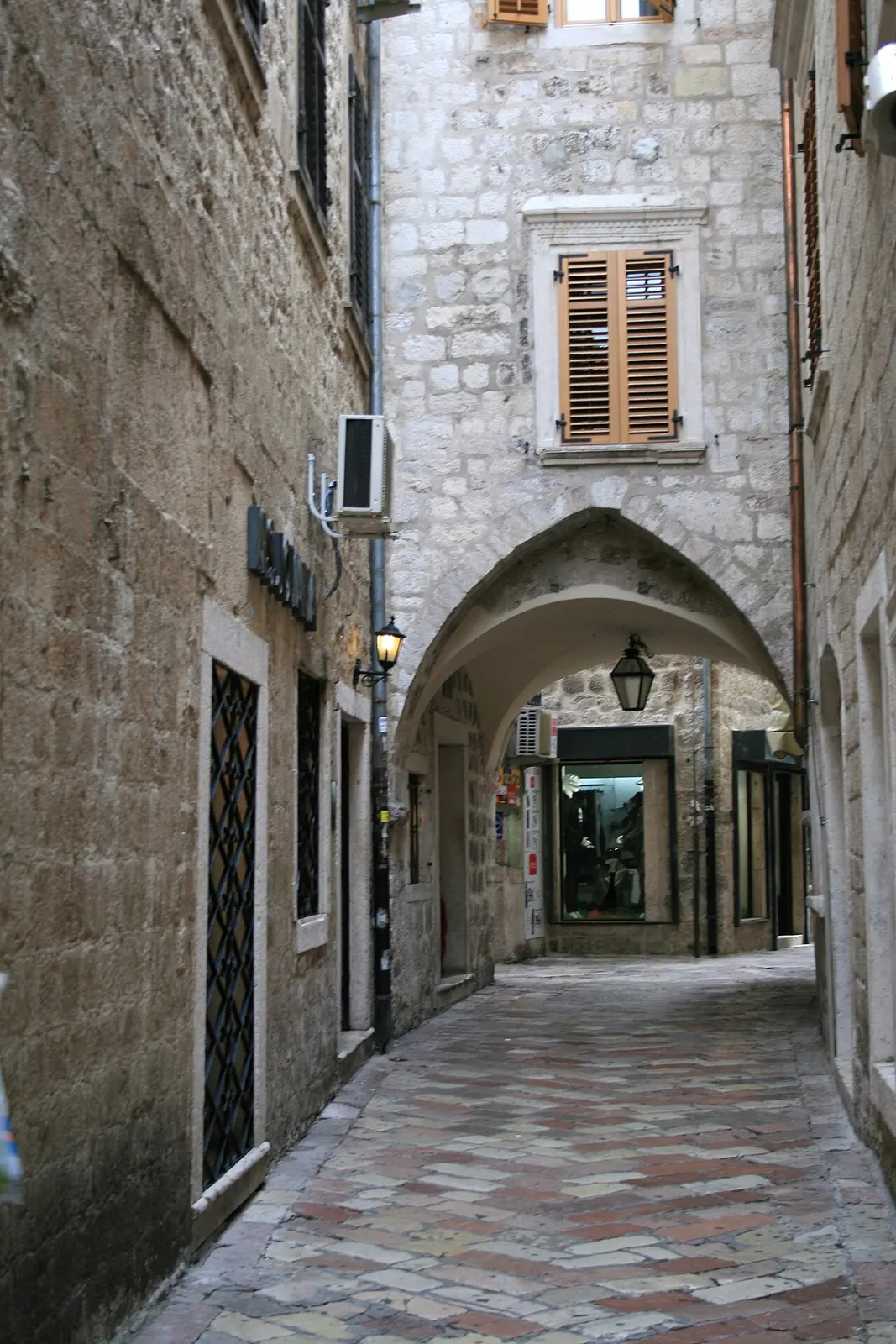 A narrow stone lane in Kotor's Old Town with worn flagstones and deep doorways
