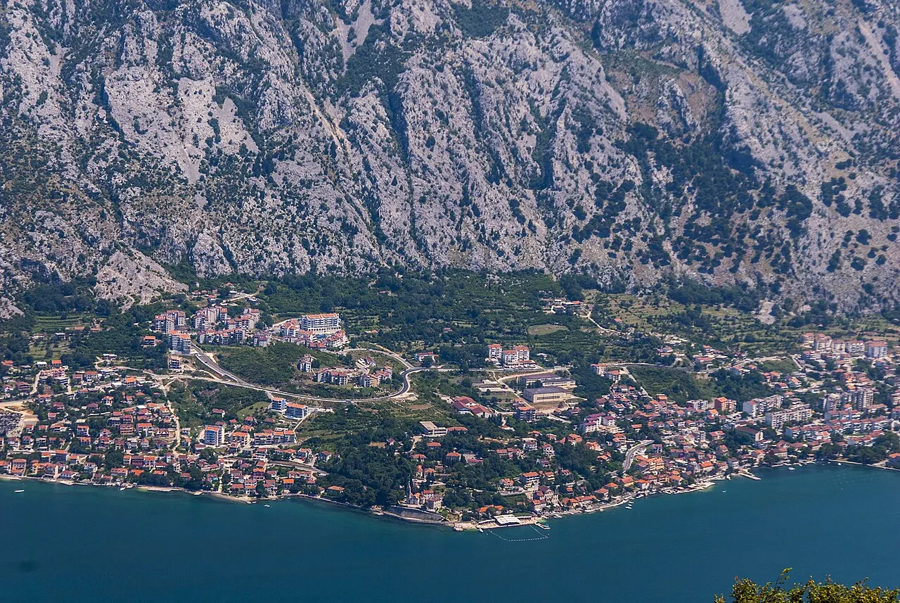 The Bay of Kotor at Dobrota glowing pink and gold as the sun sets behind the ridge