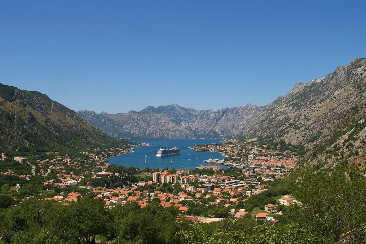 Still, deep water of the Bay of Kotor under steep green cliffs