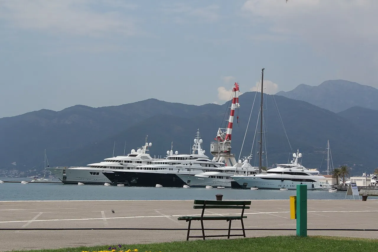 Yachts moored along the Porto Montenegro marina at Tivat with the bay mountains rising behind