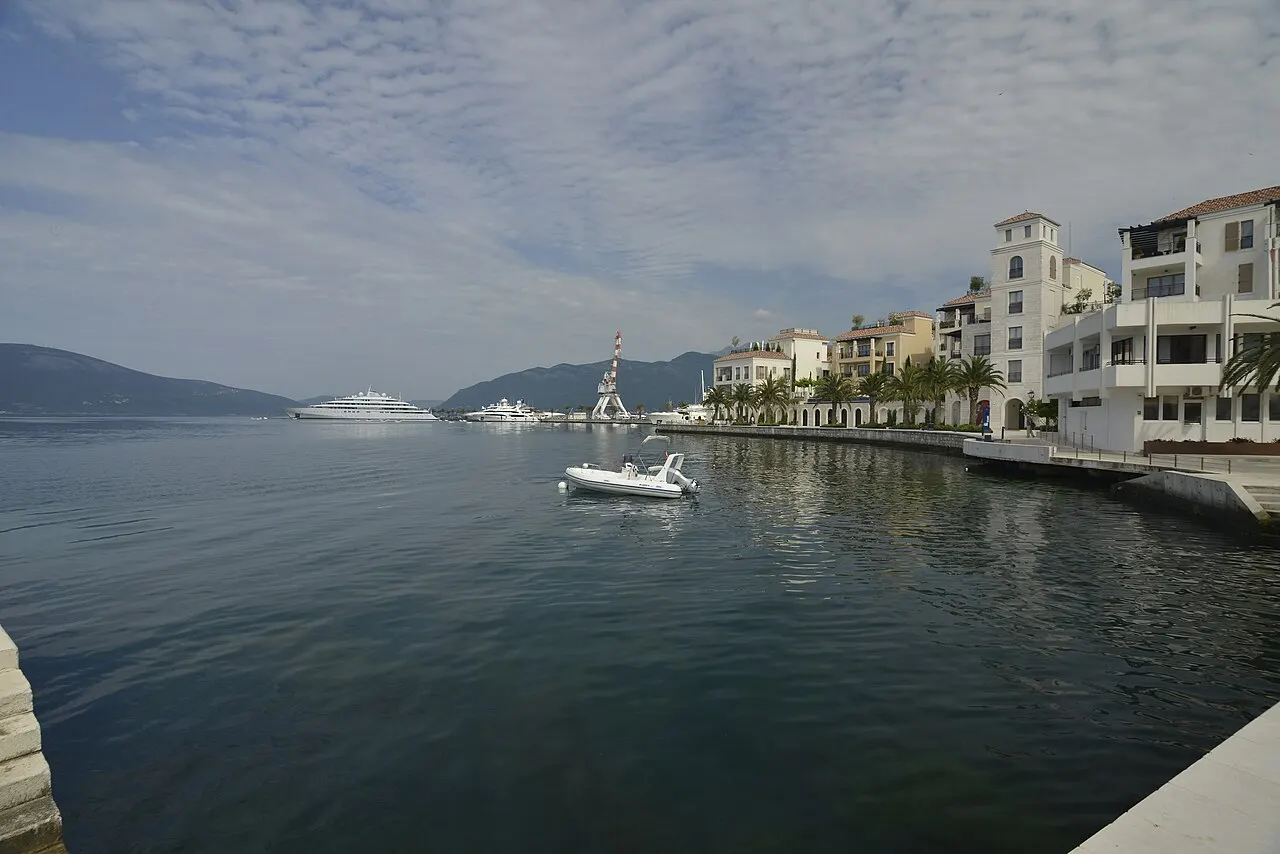 Superyachts moored along the modern promenade of Porto Montenegro in Tivat, mountains behind